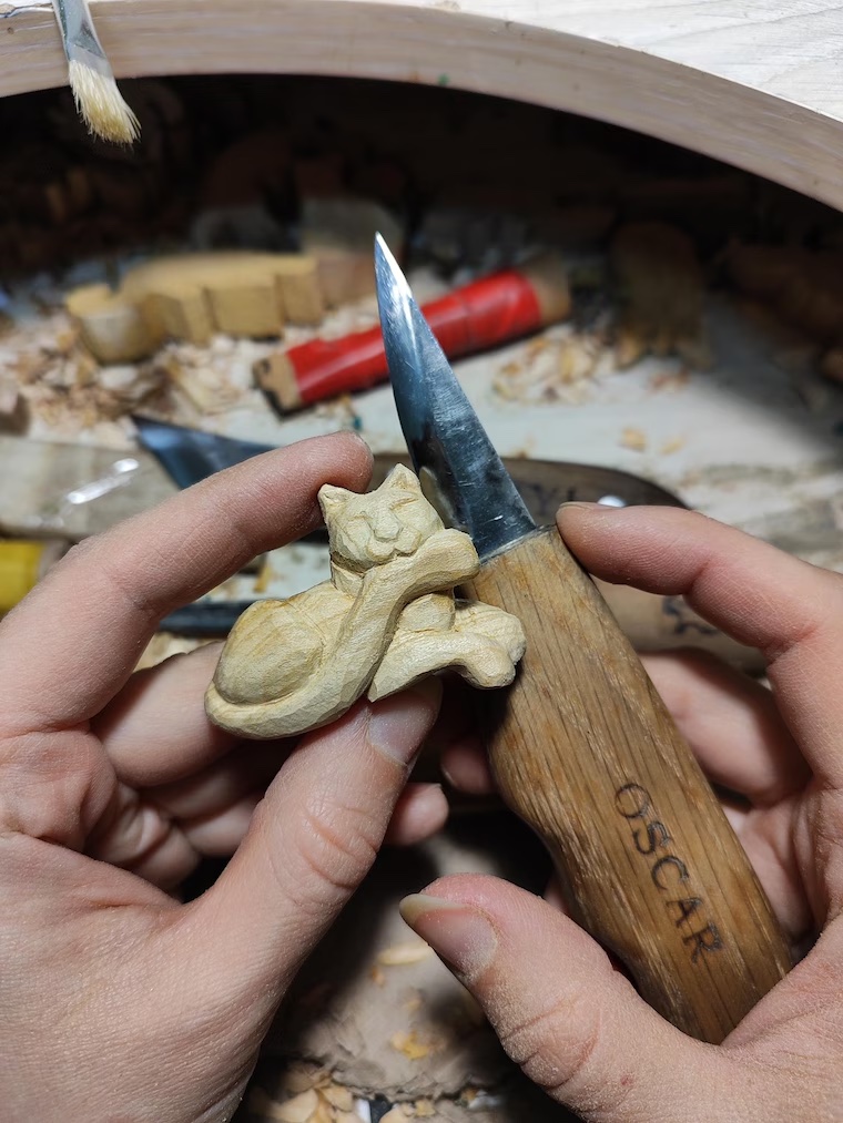 Hands carving wood at the PamPam Workshop bench